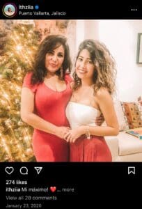 Two women posing for a picture in front of a christmas tree.